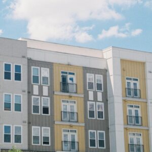 yellow, gray, white apartment building against blue sky and clouds